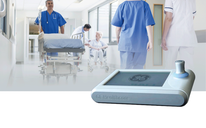 Nurses and patients in the hospital corridor. In the foreground, a control unit for ultrasound equipment with the RAFI JOYSCAPE Multi