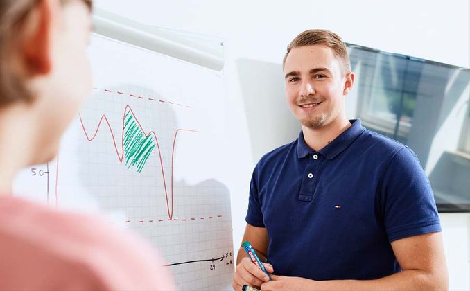 Zwei Studenten des Bereichs Wirtschaftsinformatik stehen am Flipchart.