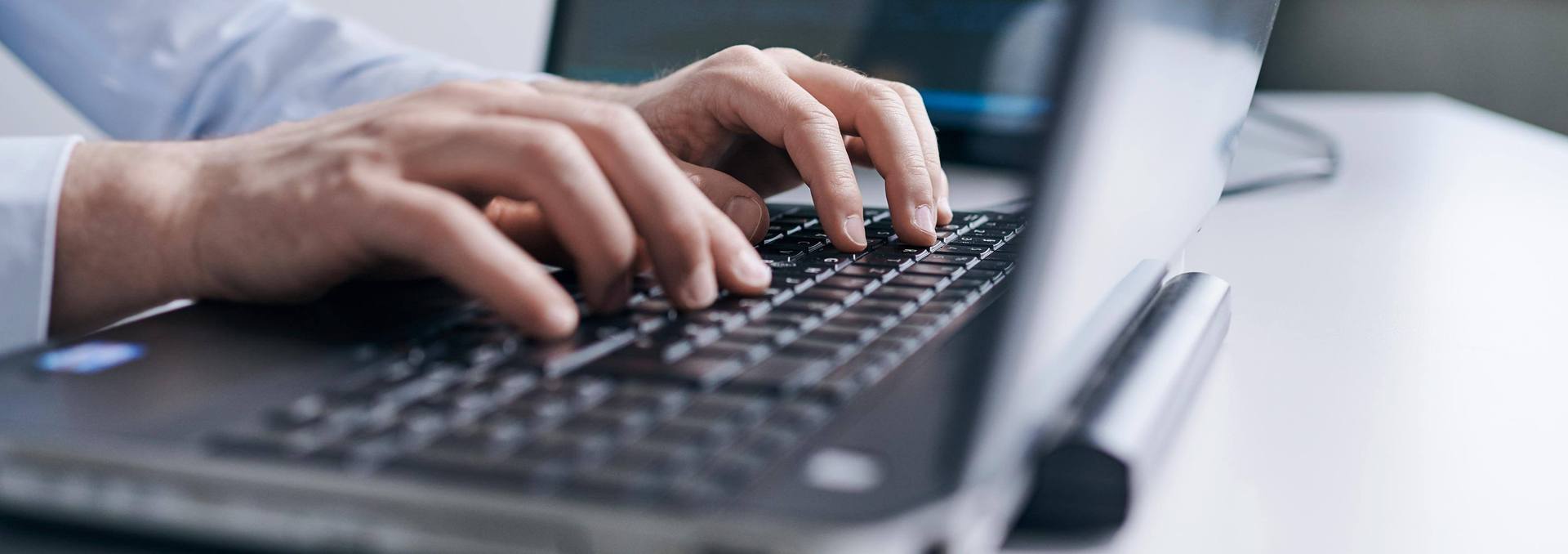 Hände eines Mitarbeiter am Laptop
